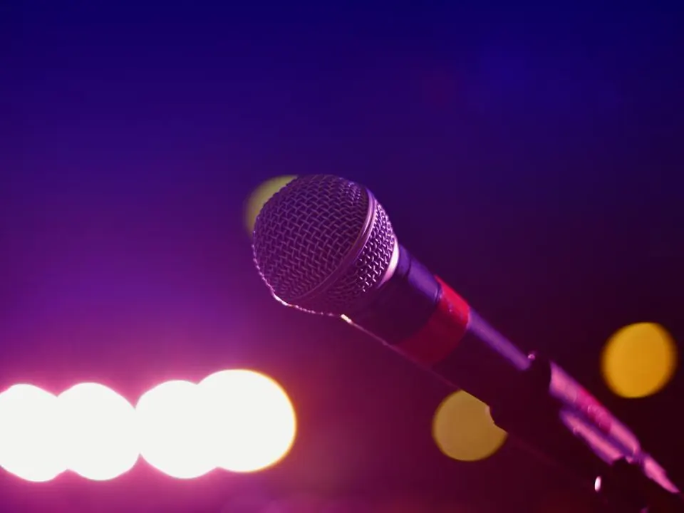 Microphone on a stand under a single spotlight on a dark stage