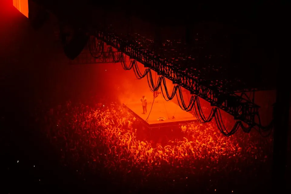 Lone performer on a stage surrounded by a massive arena crowd