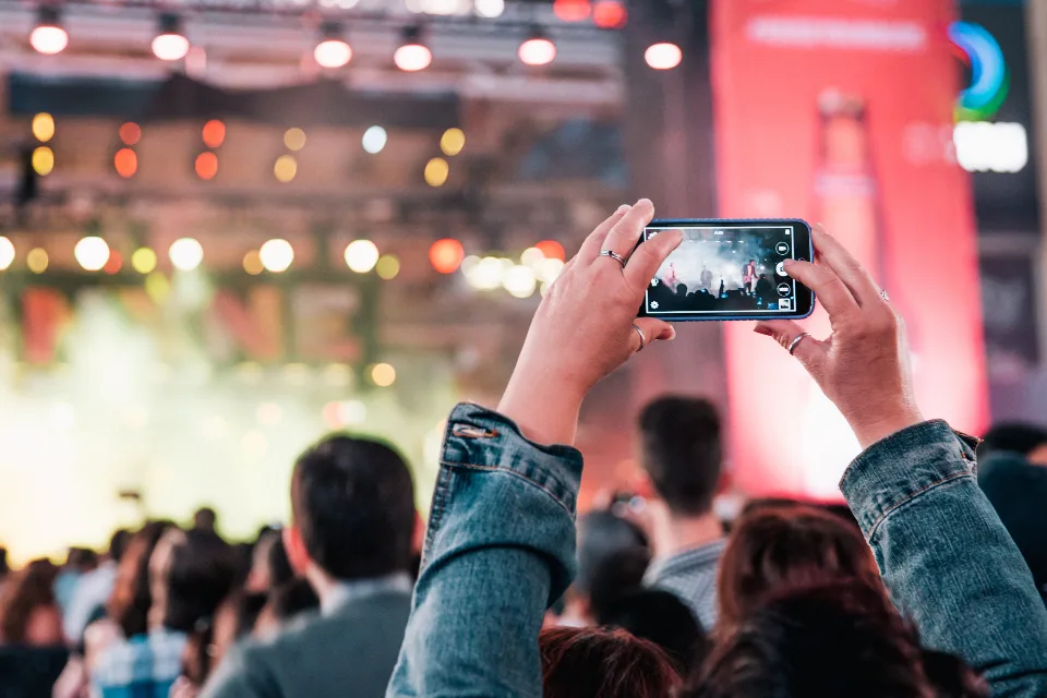 Concert audience recording a brightly lit stage on a phone