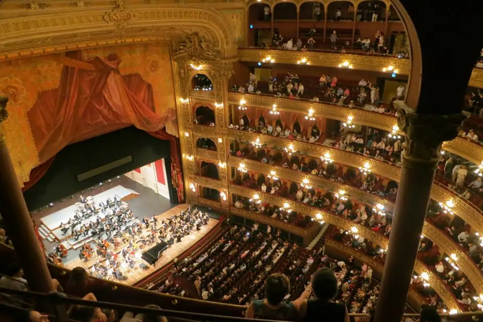 Ornate multi-tiered opera house filling with audience before a show