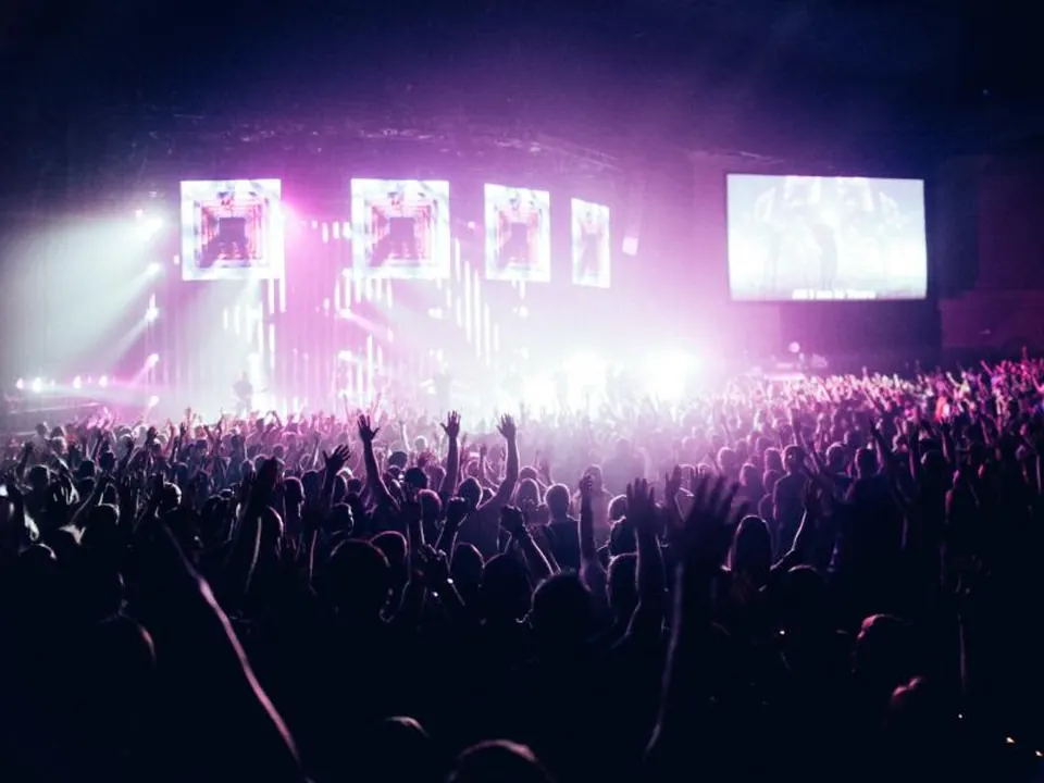 Stadium concert stage at night lit in dramatic purple and gold lighting