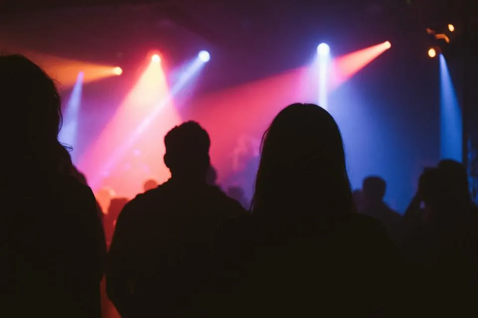 Couple silhouetted against bright stage lights at a concert