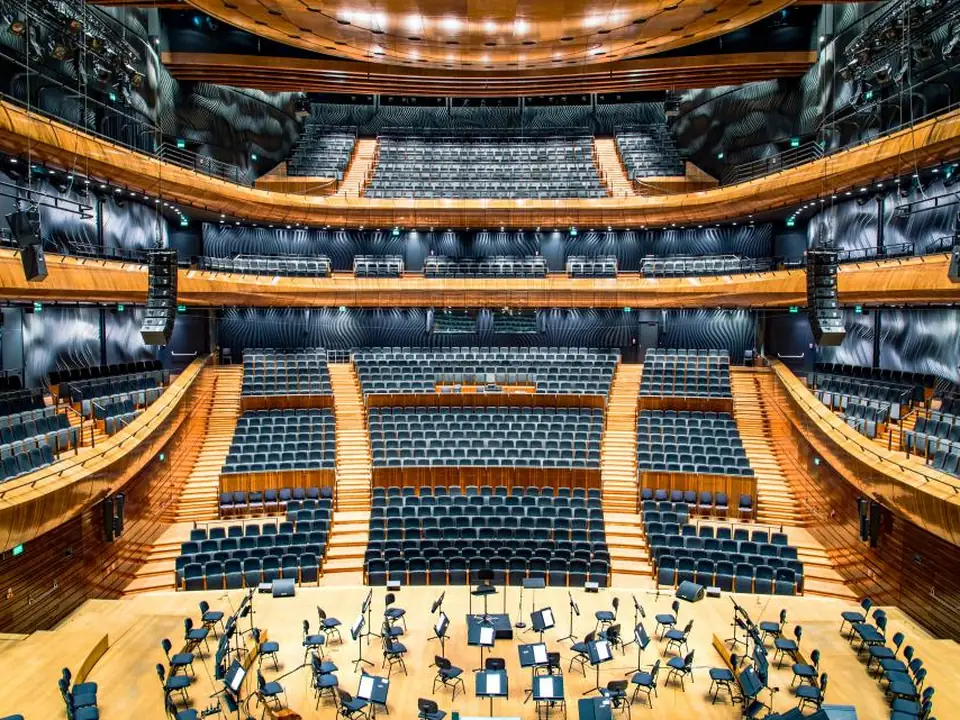 Grand tiered theater auditorium glowing in warm wood and soft light