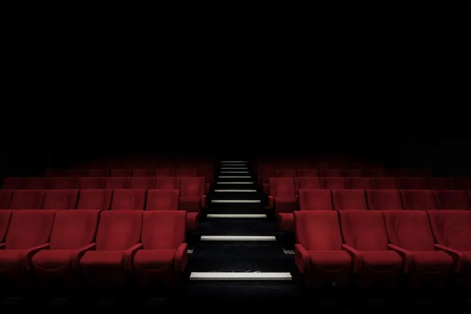 Rows of red theater seats waiting in a darkened auditorium