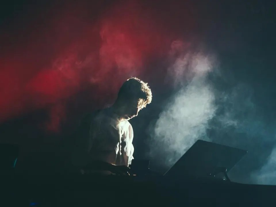 Concert stage flooded with red light and heavy smoke during a stadium rock show