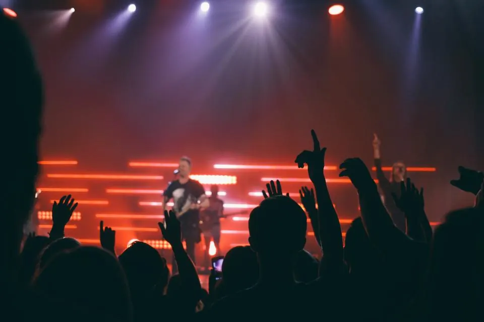 Crowd raising their hands toward the stage at a packed rock concert