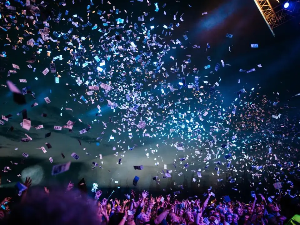 Confetti falling over a packed arena crowd during a pop concert