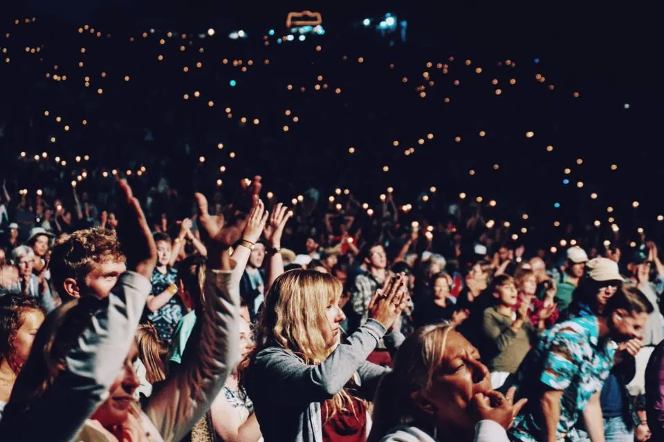 Concert audience clapping with lights raised at a night show