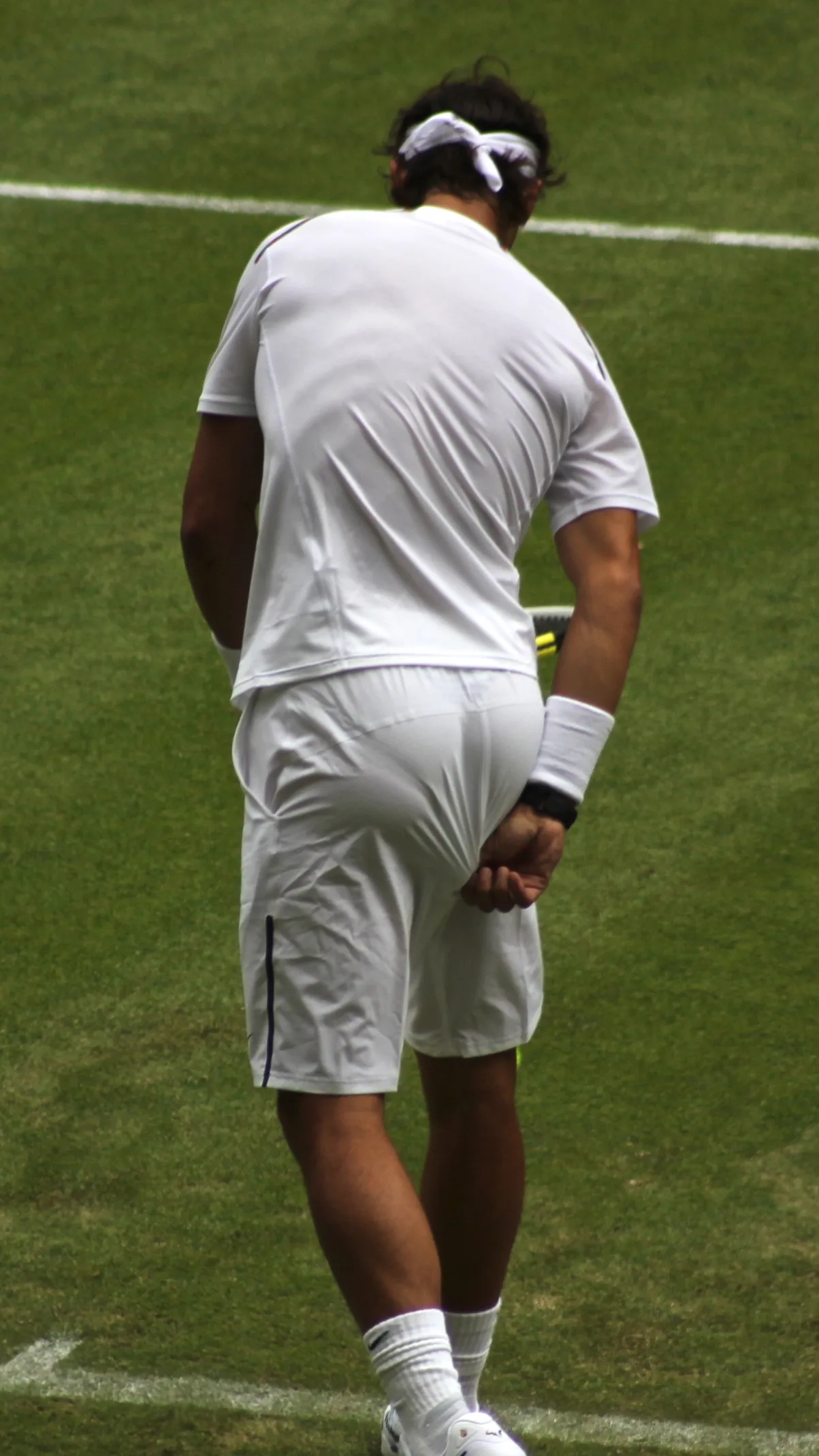 Tennis player in traditional white attire during a grass-court match