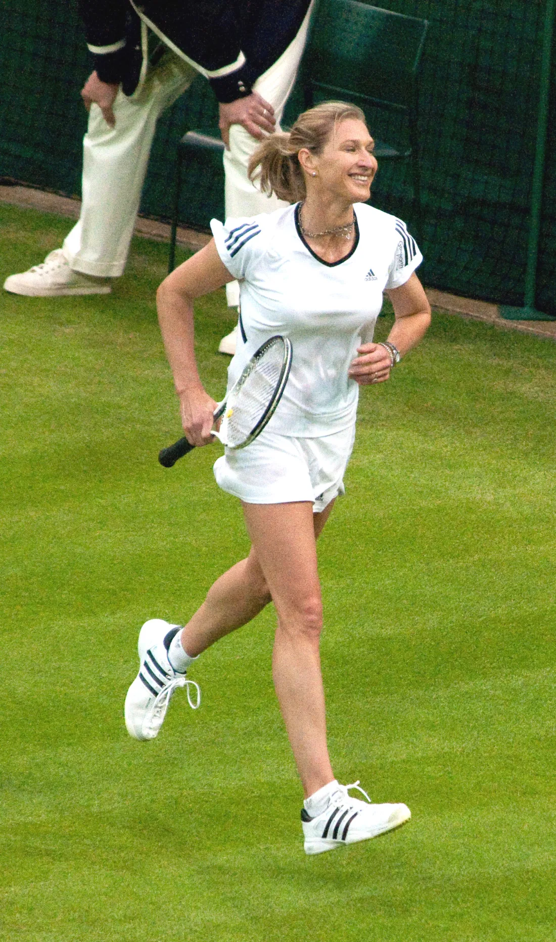 Tennis player moving across a grass court during a match