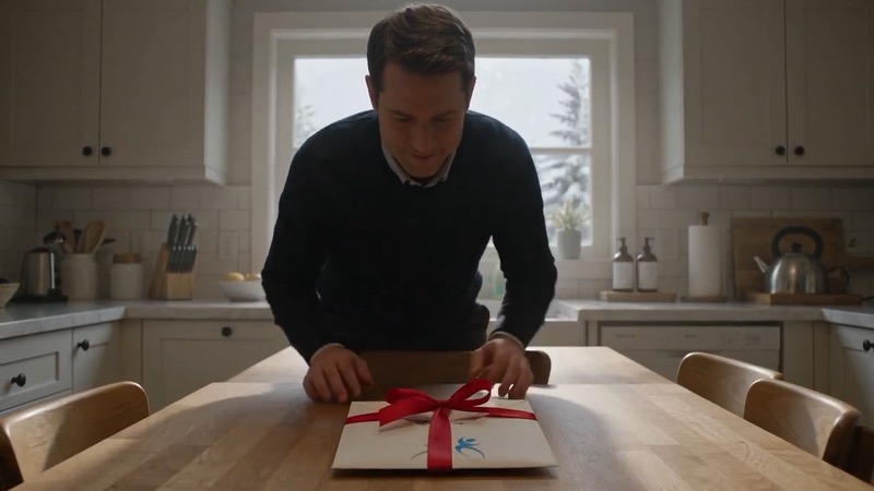 Wrapping gift tickets with a red ribbon A man ties a red ribbon around a StubOrder envelope holding gift tickets