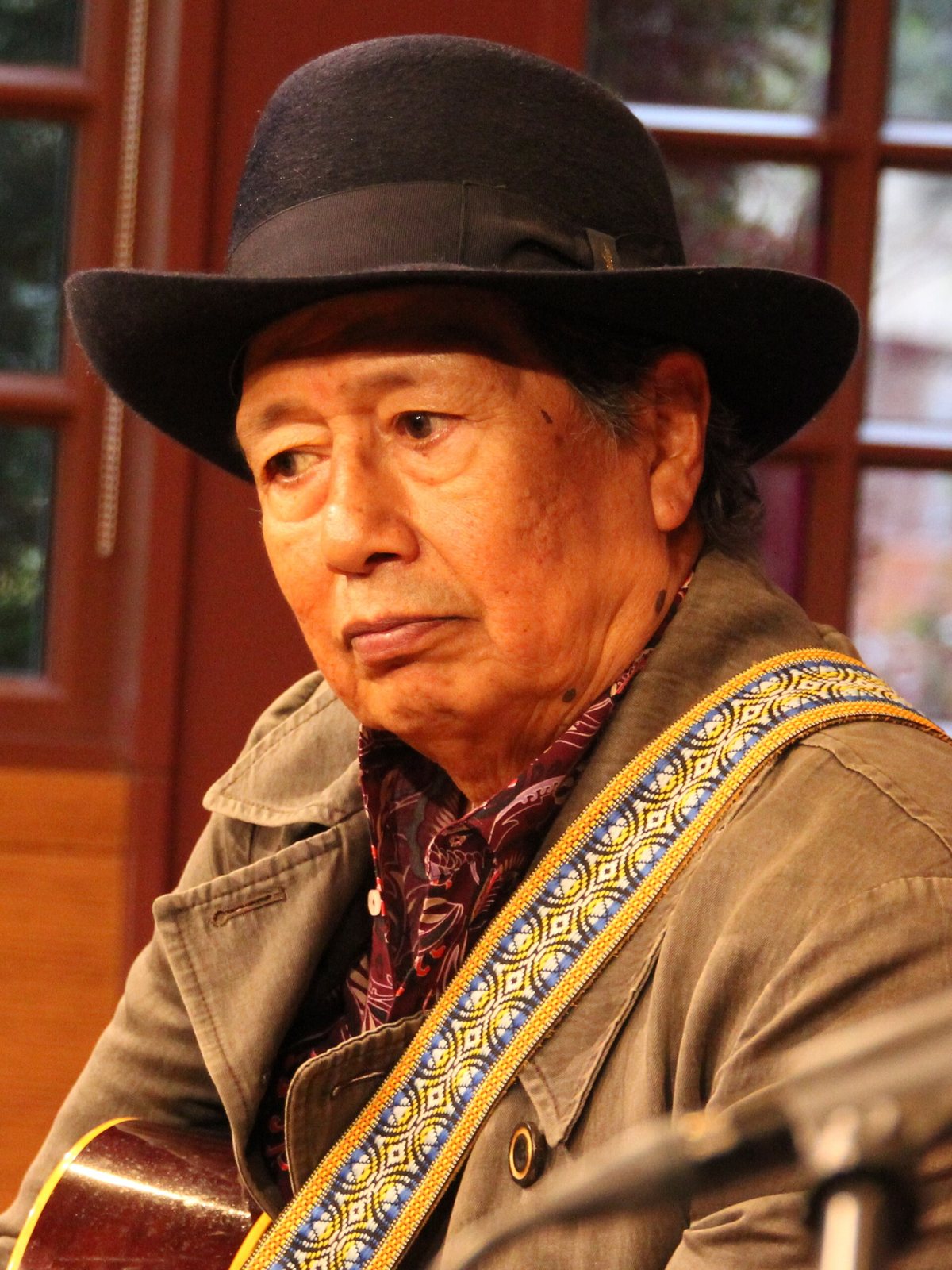 Alejandro Escovedo with an acoustic guitar at a microphone, 2024