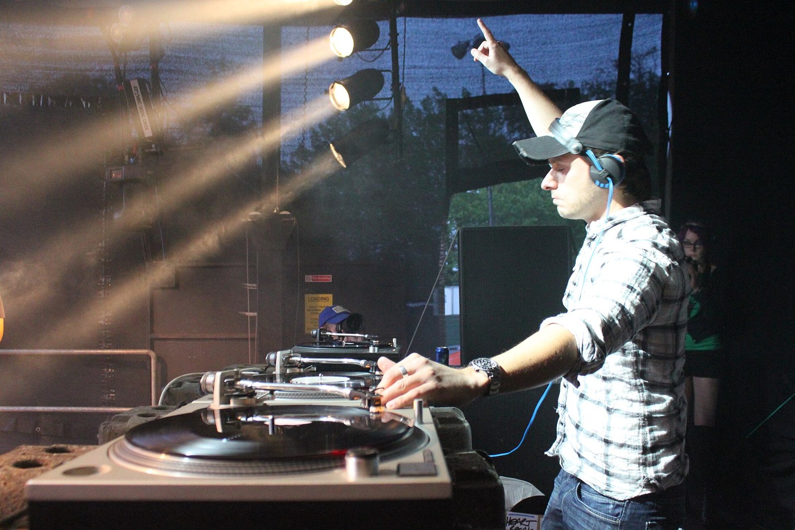 Andy C DJing on vinyl turntables with an arm raised during a live set in 2011