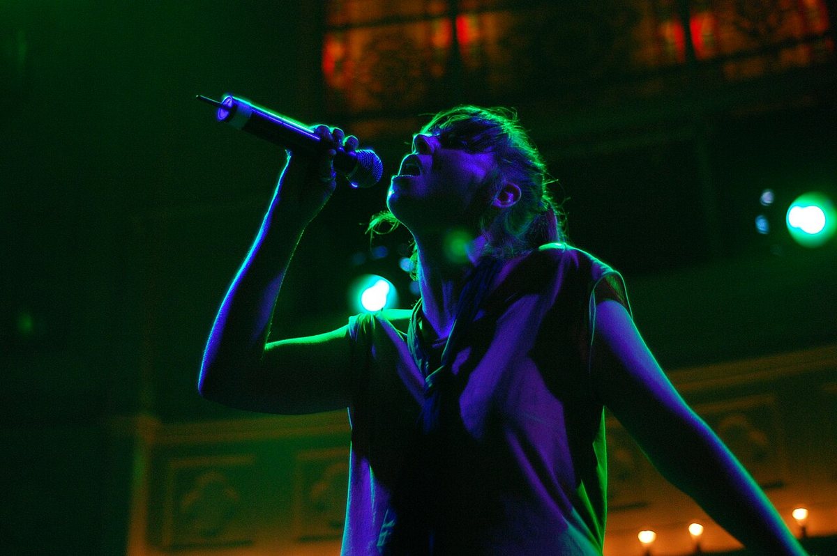 Cat Power singing into a microphone under green and purple stage lights, 2008