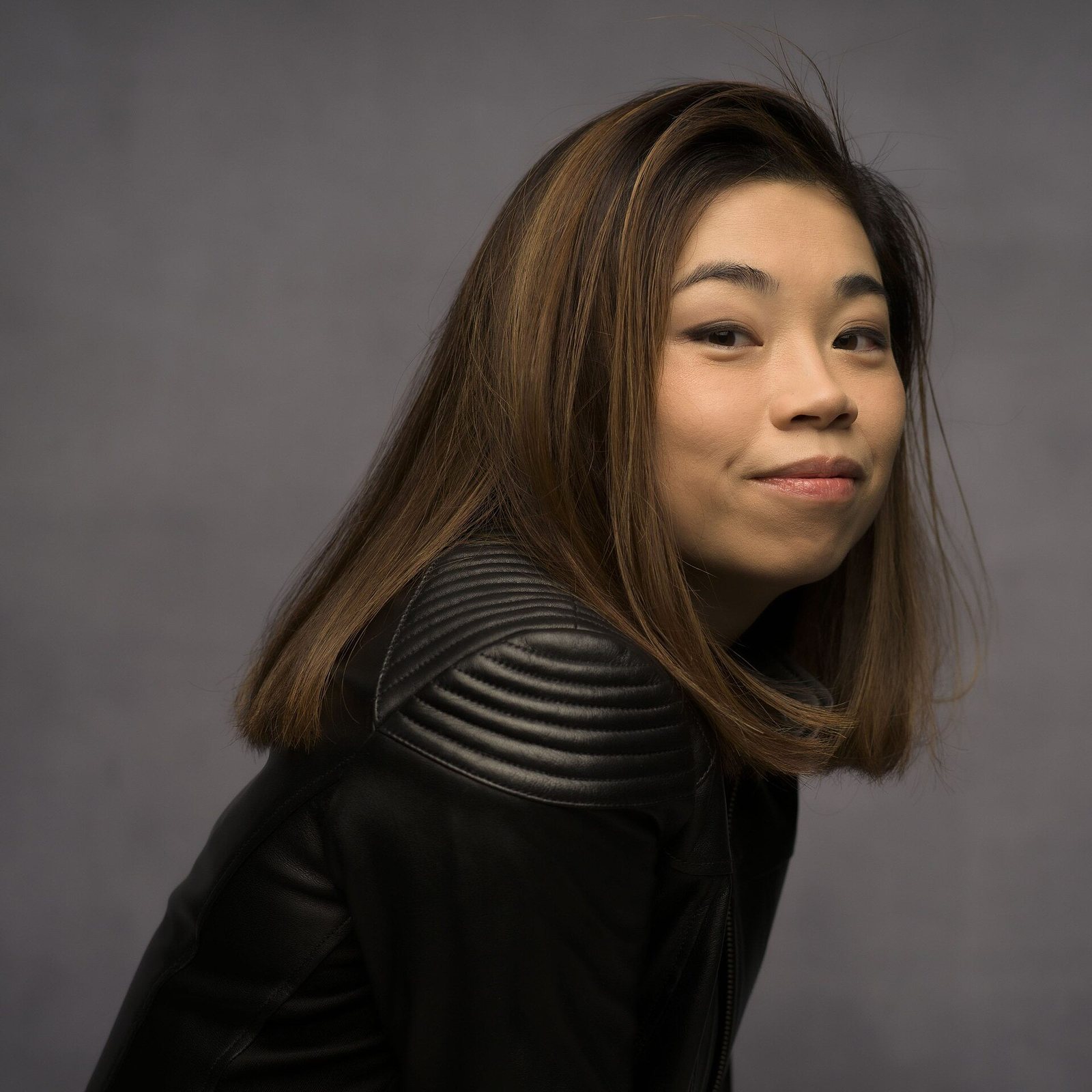 Conductor Elim Chan in a black leather jacket, studio portrait by Marco Borggreve