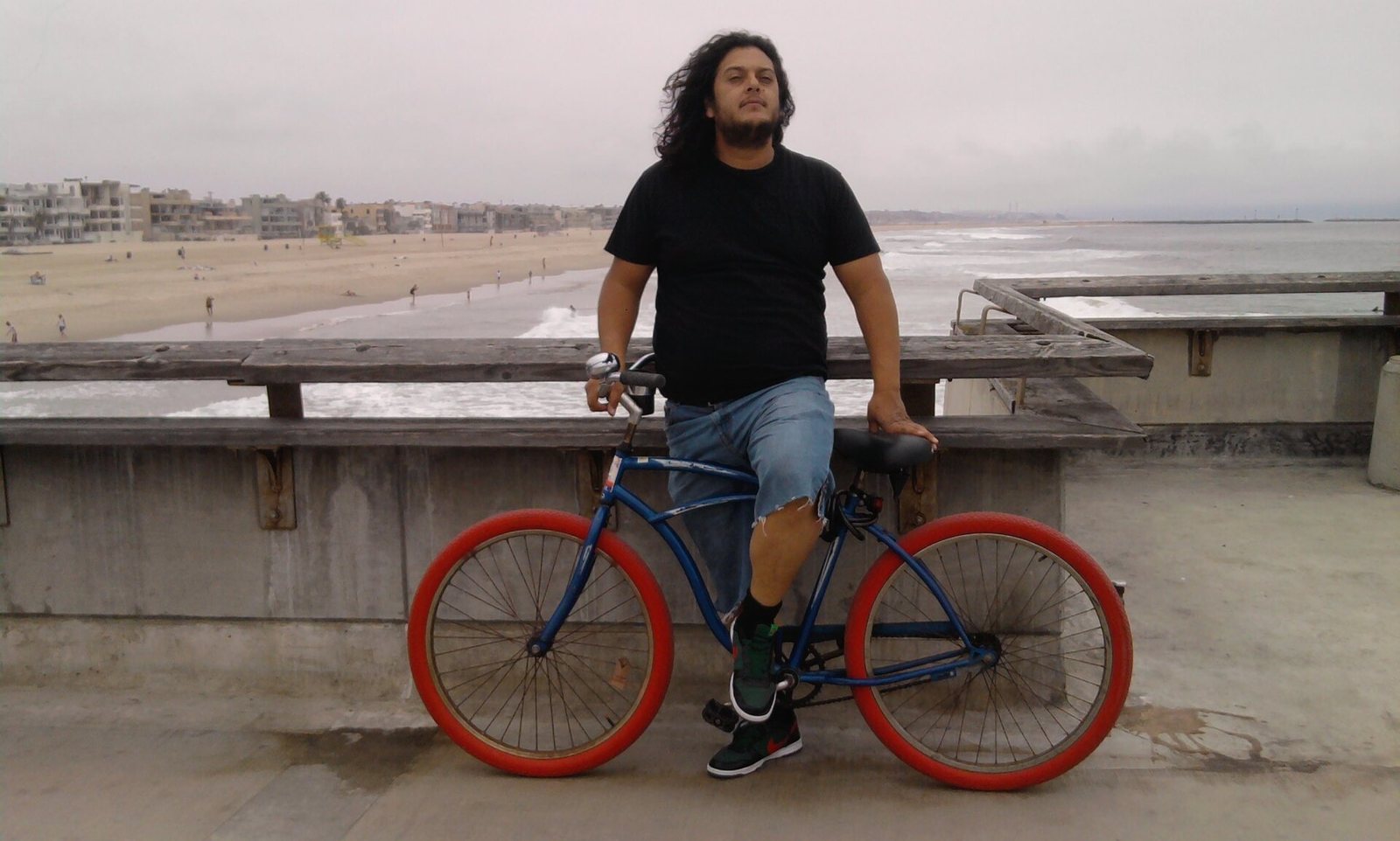 Comedian Felipe Esparza standing with his bicycle at Venice Beach, California, 2010