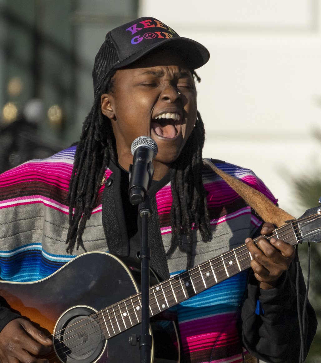 Joy Oladokun singing with an acoustic guitar on the South Lawn of the White House, December 2022