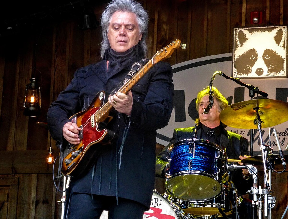 Marty Stuart playing electric guitar on stage at MerleFest 2017, with his drummer behind him