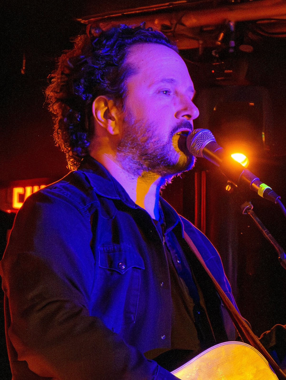 Mason Jennings singing with an acoustic guitar on stage, 2025