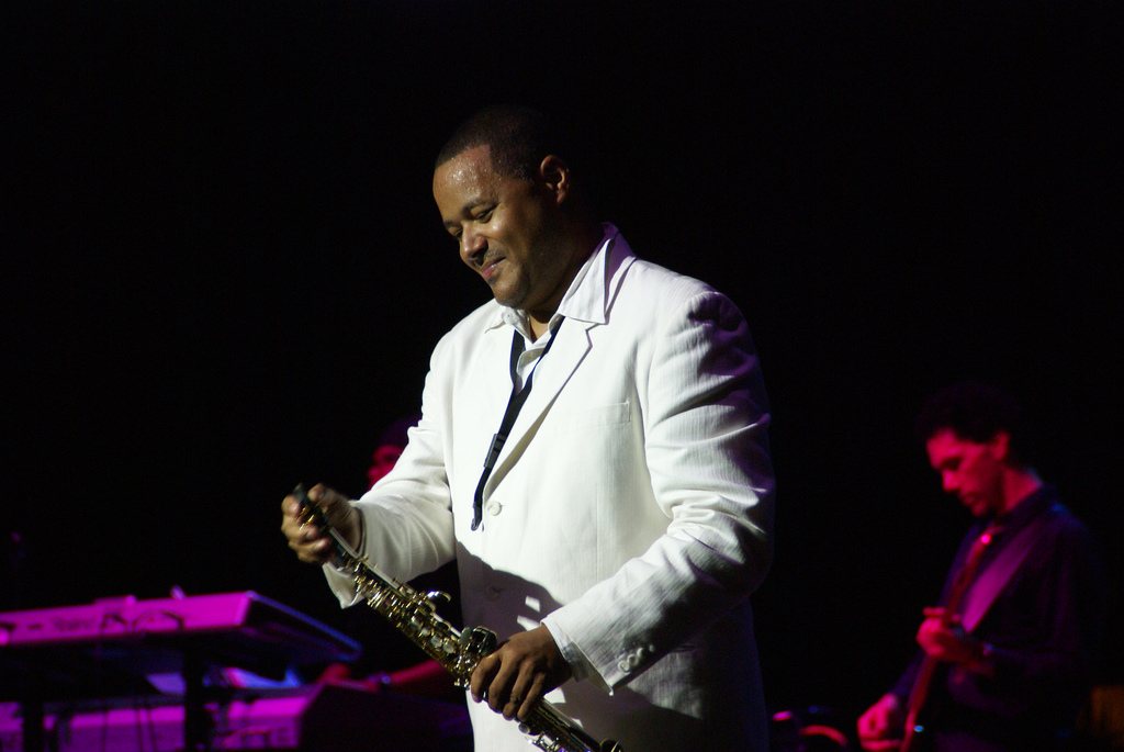 Najee on stage in a white suit holding his soprano saxophone, 2007