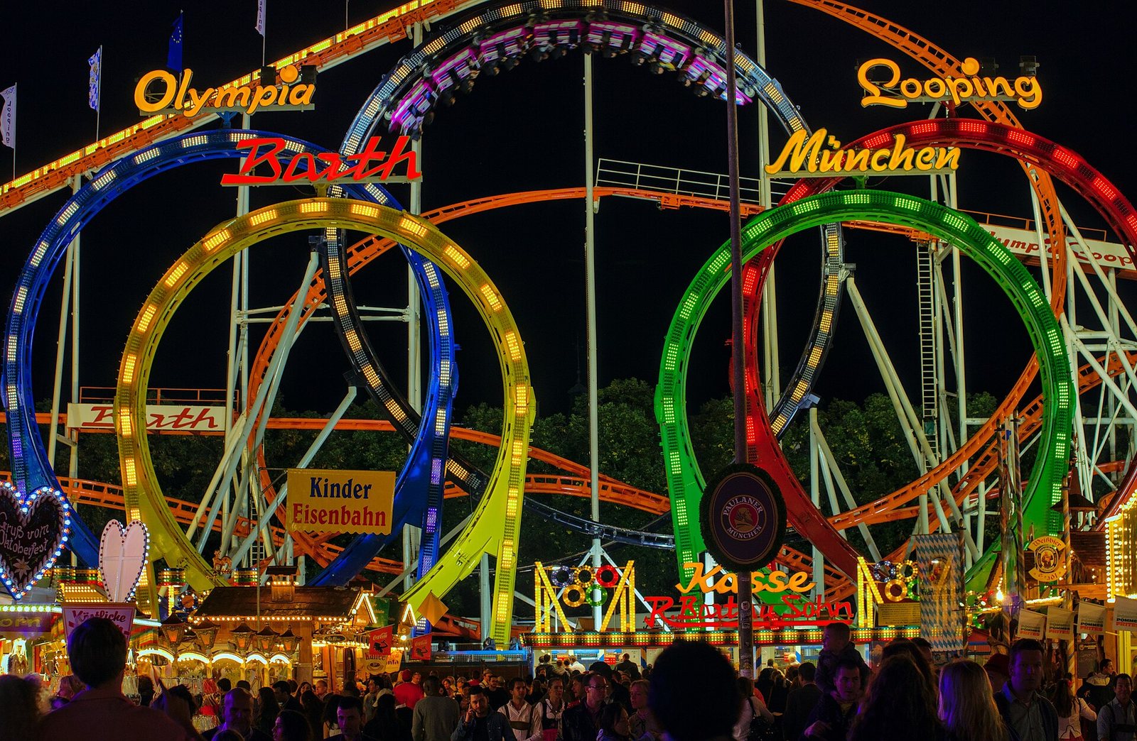 Olympia Looping roller coaster lit up at night above the crowds at Munich Oktoberfest on the Theresienwiese, 2012