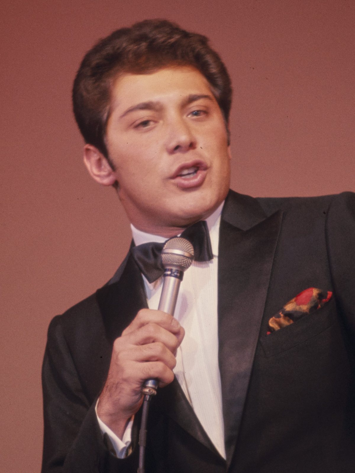 Paul Anka singing into a microphone in a tuxedo, photographed by Bernard Gotfryd in the 1960s