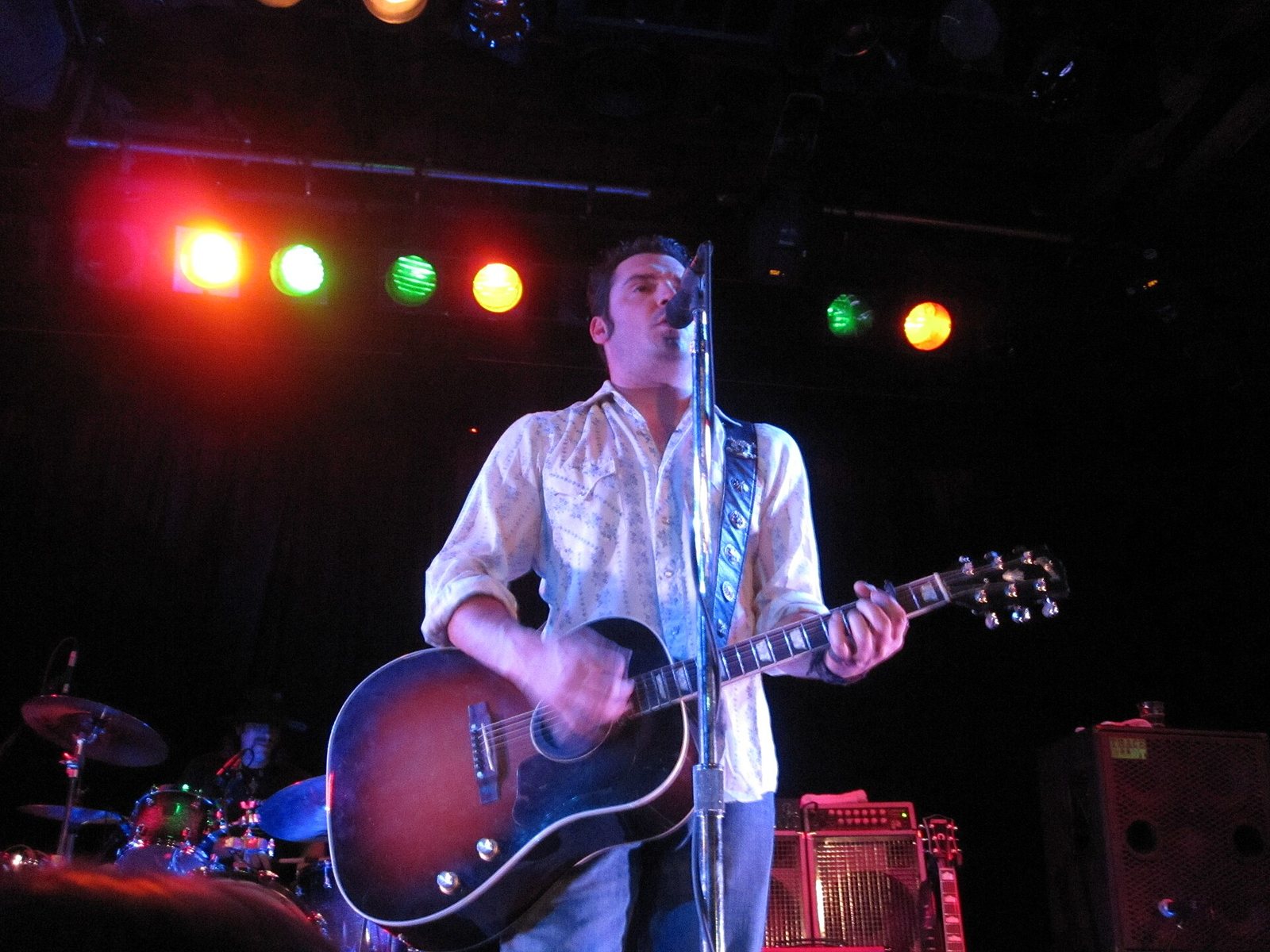 Willy Braun of Reckless Kelly singing with an acoustic guitar on stage, 2010