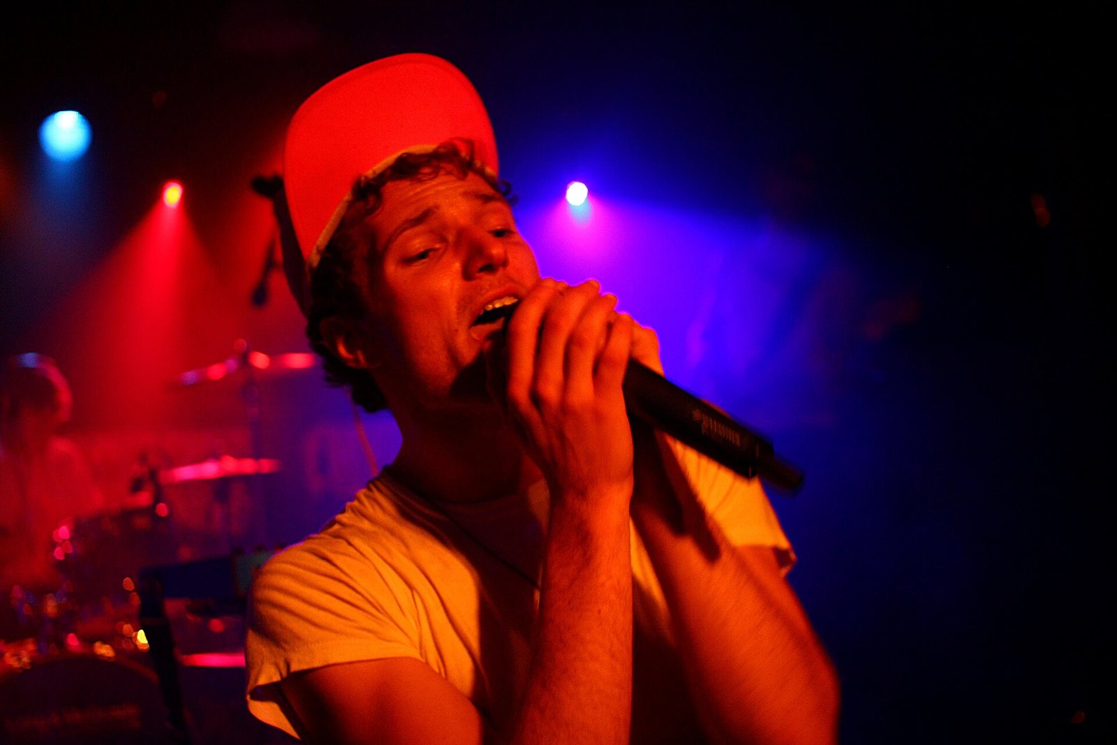 Rich Aucoin singing into a microphone on stage under red and blue lights, 2010