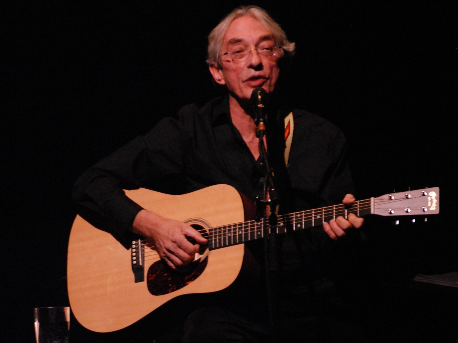 Richard Desjardins singing with an acoustic guitar in concert at Arvida, Saguenay, 2012