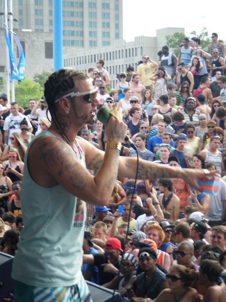 Rapper Riff Raff performing on stage in front of a large outdoor crowd