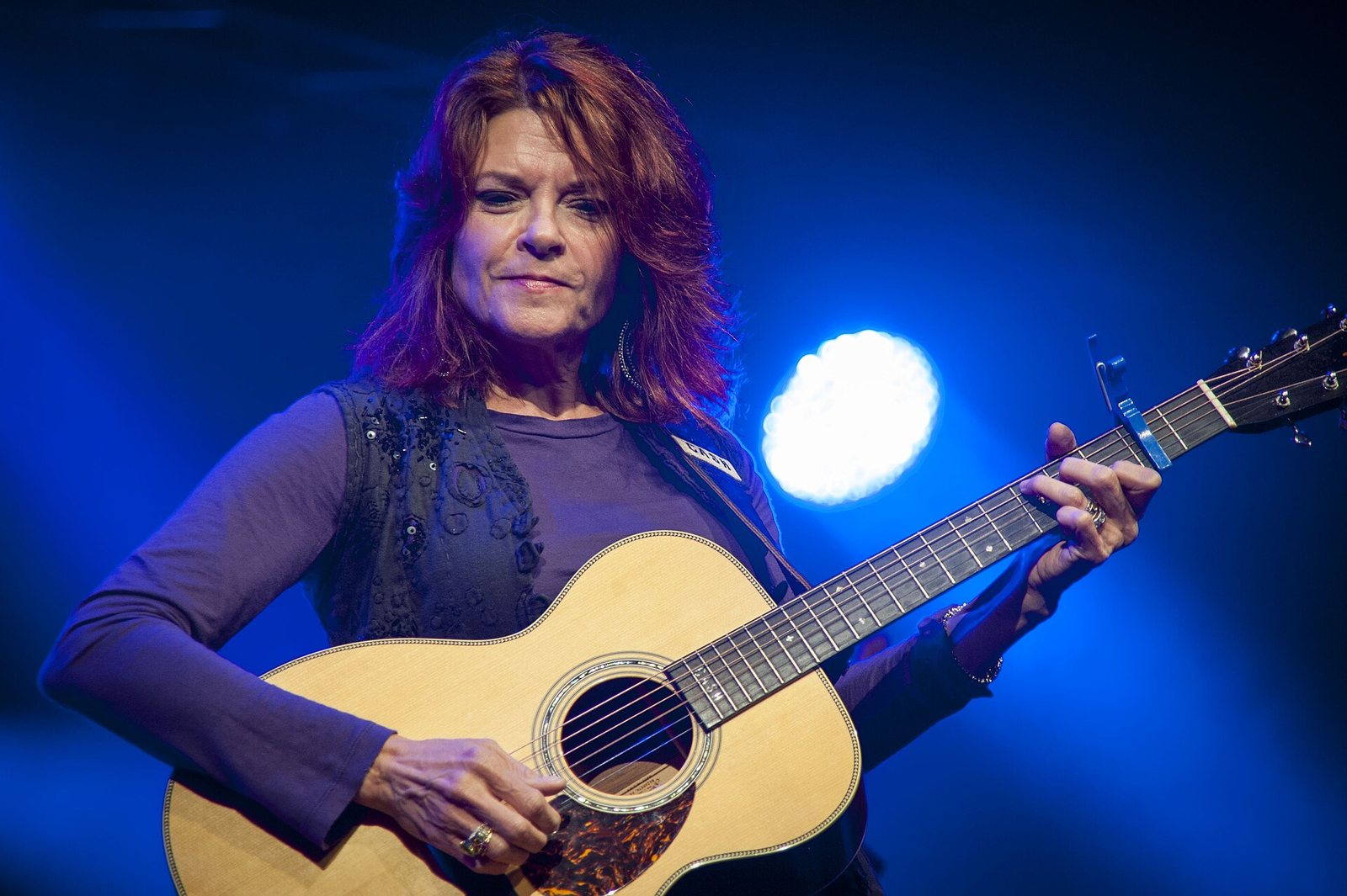 Rosanne Cash playing acoustic guitar on stage at the Cambridge Folk Festival 50th anniversary, 2014