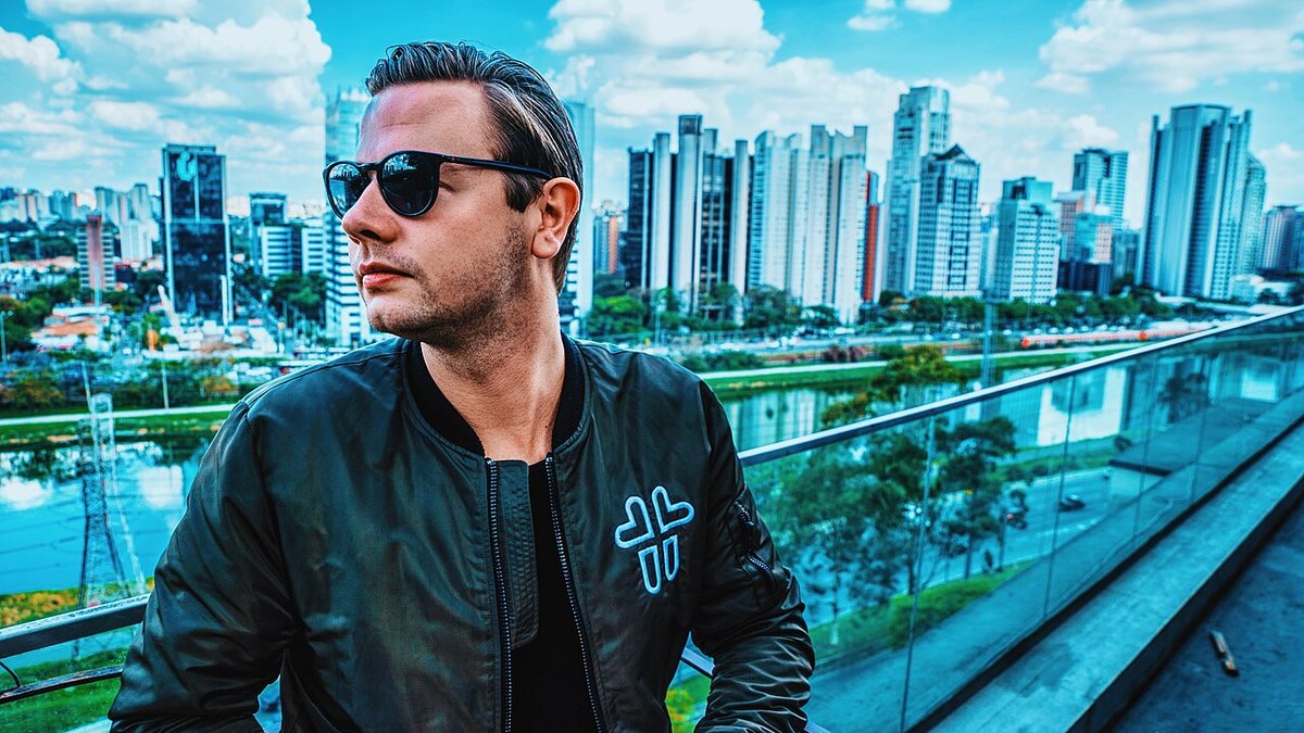 Sam Feldt in sunglasses and a bomber jacket on a rooftop above a city skyline