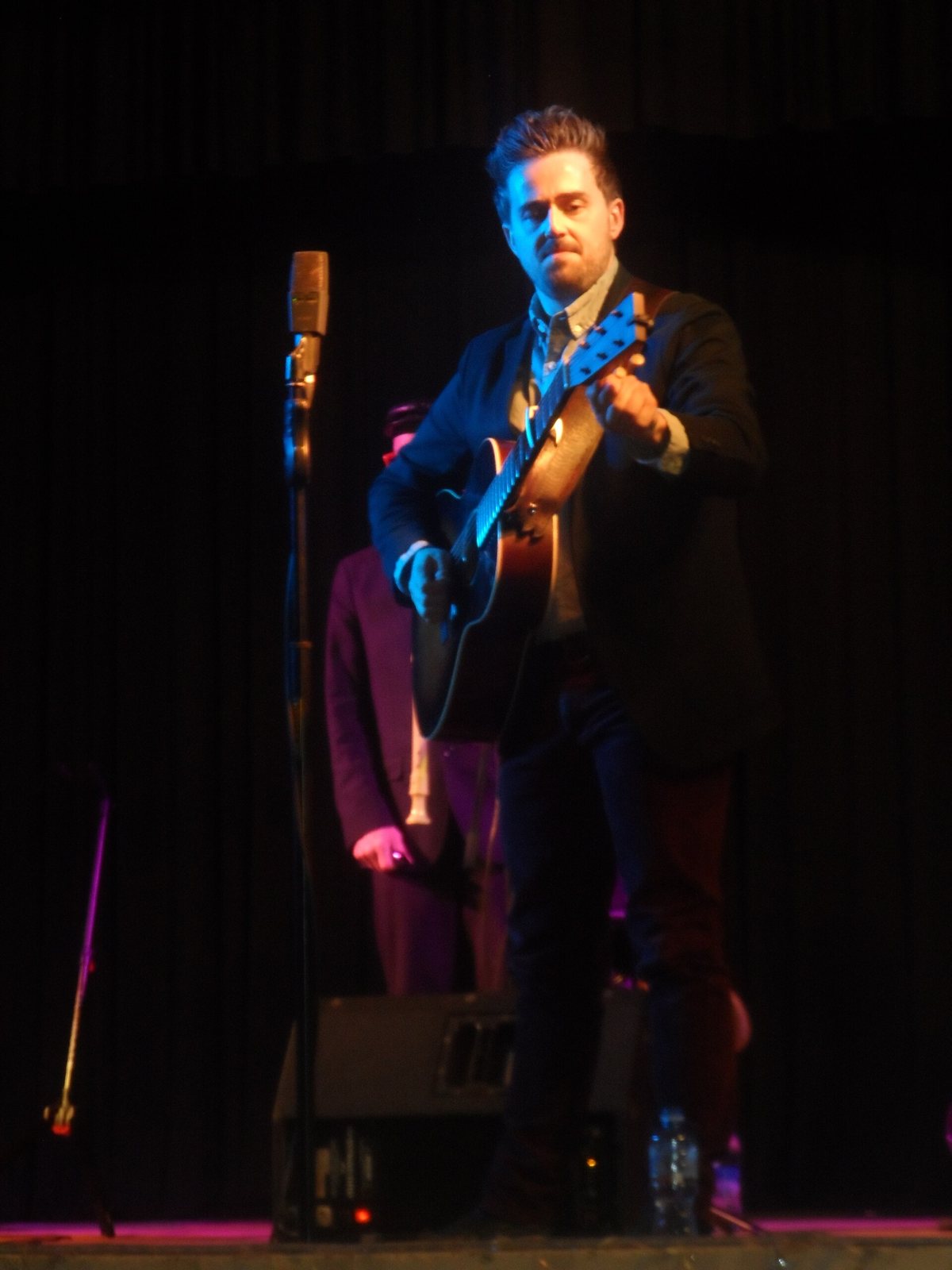Seth Glier playing acoustic guitar on stage in Melitopol, Ukraine, 2018