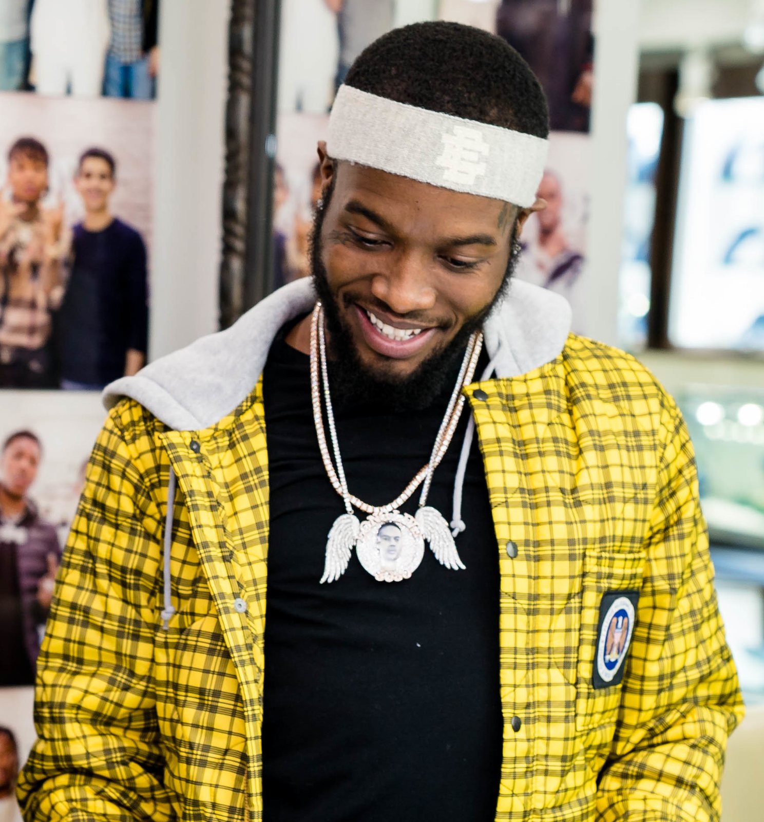 Shy Glizzy smiling in a yellow plaid jacket and pendant chain, 2018