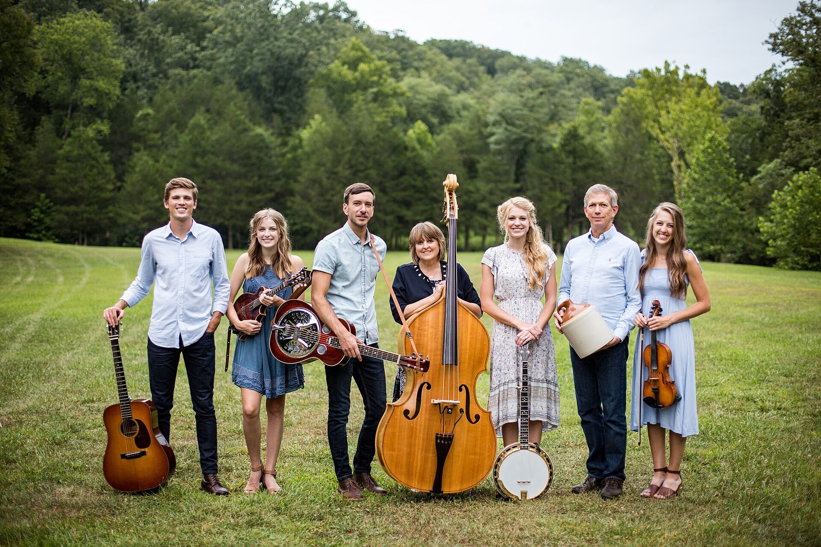 The Petersens bluegrass family band posing with their instruments in a field, 2020