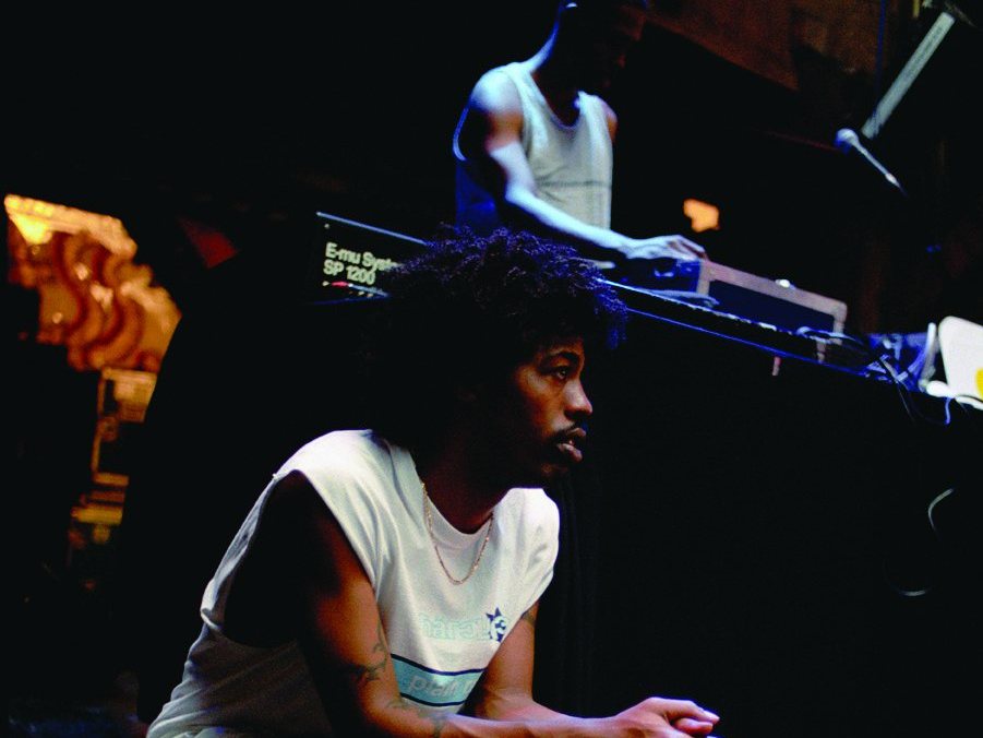 A member of The Pharcyde seated on stage in front of the DJ, Hamburg, Germany, 1999
