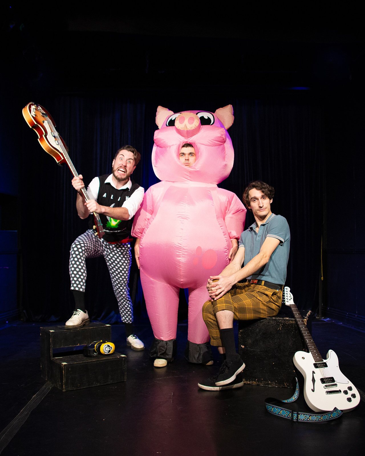 The Toxhards posing on stage with guitars and a bandmate in an inflatable pink pig costume, 2024