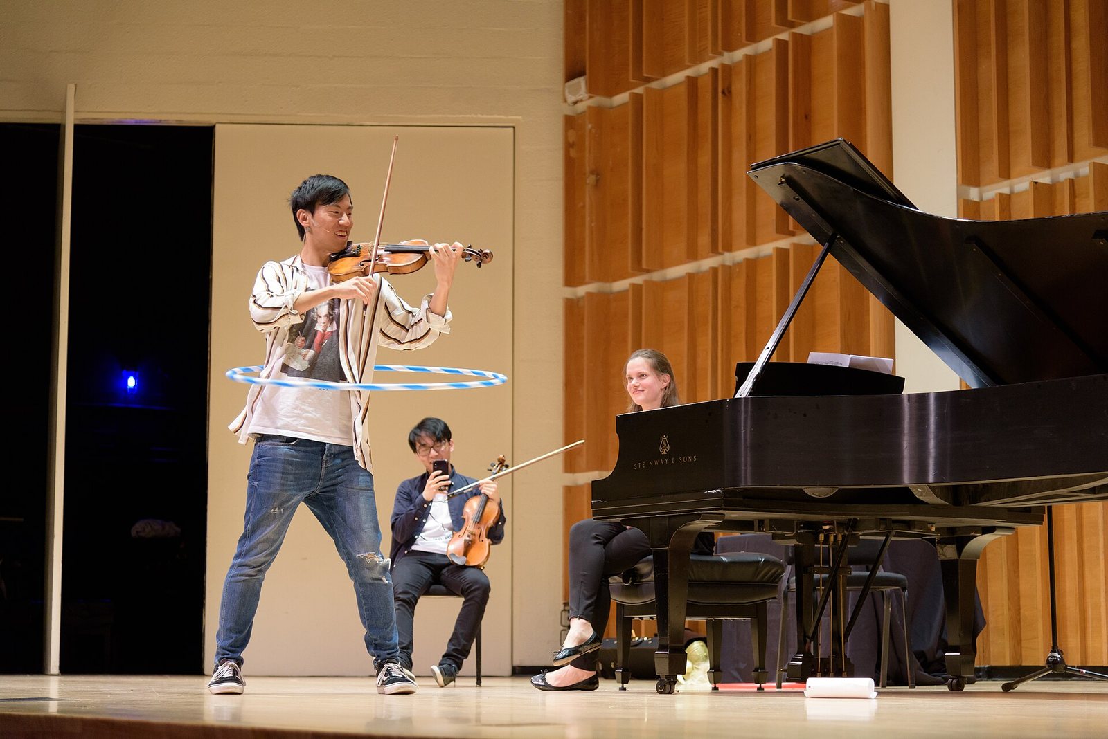 TwoSet Violin's Eddy Chen playing violin while hula hooping at Merkin Concert Hall, New York, 2018