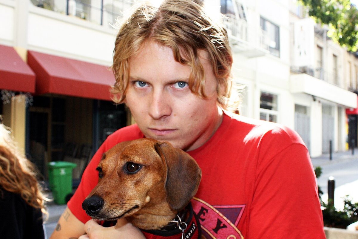Ty Segall holding his dachshund Fanny on a street, 2016
