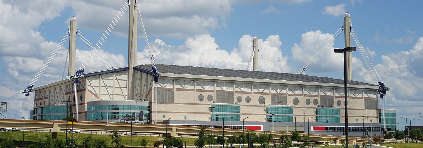 Exterior of the Alamodome stadium in San Antonio, Texas, showing its four cable-stayed roof masts from the adjacent parking lot - Alamodome tickets