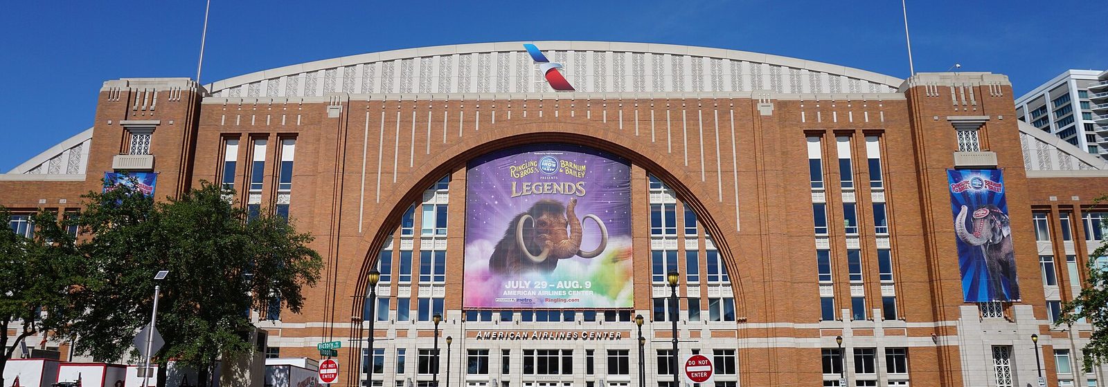 Airports near American Airlines Center Front facade of the American Airlines Center in Dallas, Texas, with its brick arched entrance and rooftop American Airlines logo under a clear sky - American Airlines Center tickets