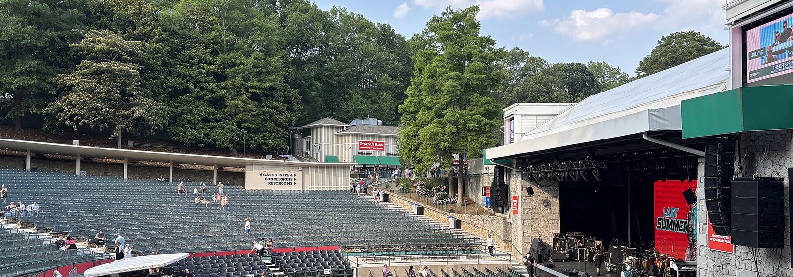 View across the tree-lined seating bowl toward the covered stage of the Chastain Park amphitheatre (now Synovus Bank Amphitheater, formerly Cadence Bank Amphitheatre) in Atlanta, Georgia - Cadence Bank Amphitheatre at Chastain Park tickets