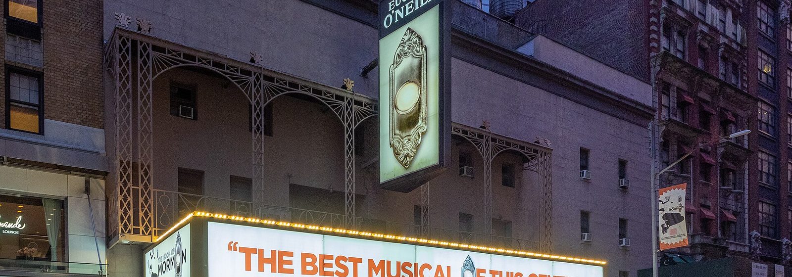 Facade of the Eugene O'Neill Theatre on West 49th Street in Midtown Manhattan at dusk, with its lit marquee and vertical sign - Eugene O'Neill Theatre tickets