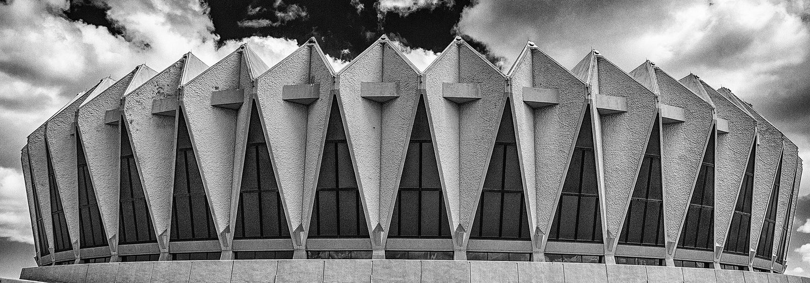 Black-and-white exterior view of the crown-shaped concrete facade of Hampton Coliseum in Hampton, Virginia - Hampton Coliseum tickets