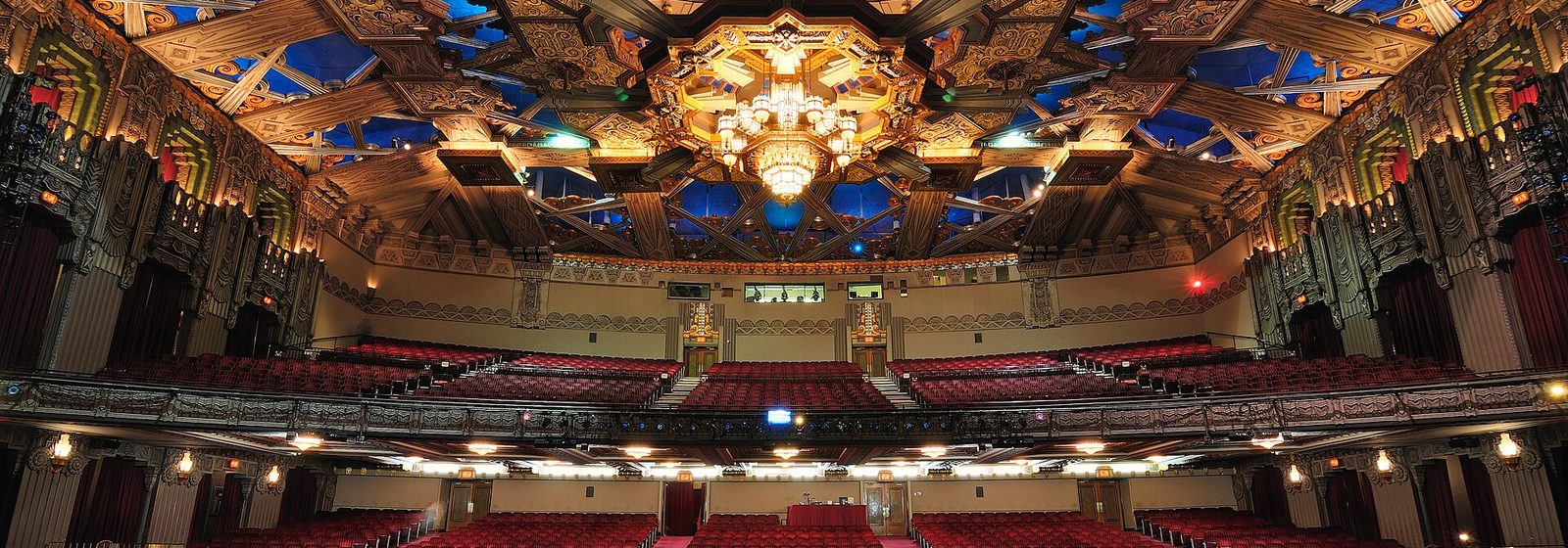 Wide interior view from the stage of the Hollywood Pantages Theatre in Los Angeles, showing the ornate Art Deco ceiling and rows of red seats - Hollywood Pantages Theatre - CA tickets