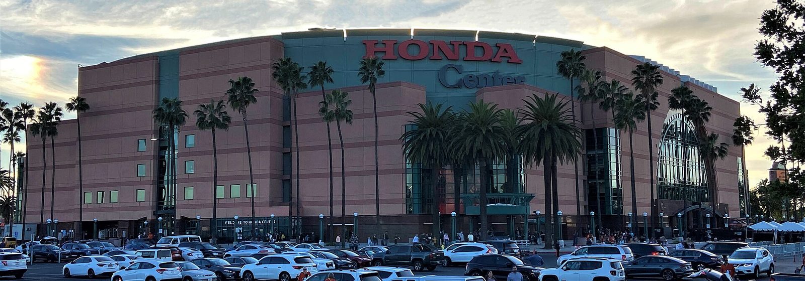 Airports near Honda Center Exterior view of the Honda Center arena in Anaheim, California, showing its curved facade, rooftop signage, and palm-lined entrance from the parking lot - Honda Center tickets
