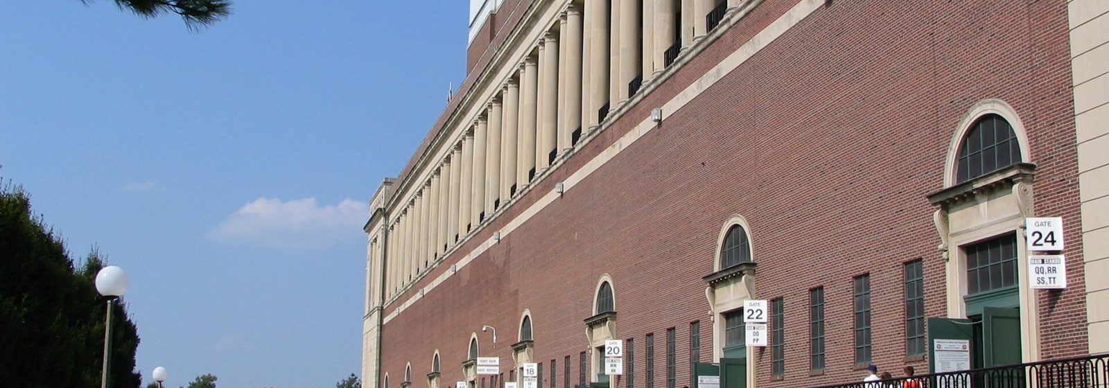 West facade colonnade of Memorial Stadium in Champaign, Illinois, with fans walking toward the numbered gates before a football game - Memorial Stadium - IL tickets