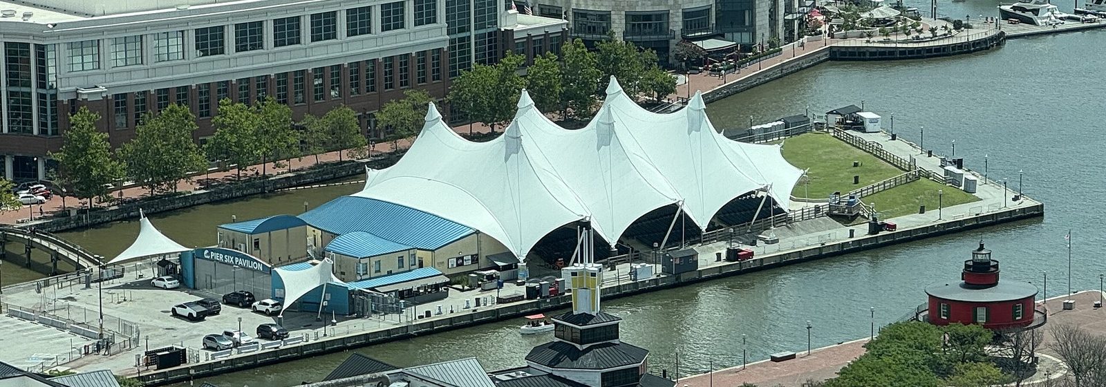 Exterior view of the Pier Six Pavilion, an open-air concert venue with a white tent-like roof on the Inner Harbor in Baltimore, Maryland, seen from the Baltimore World Trade Center - Pier Six Pavilion tickets