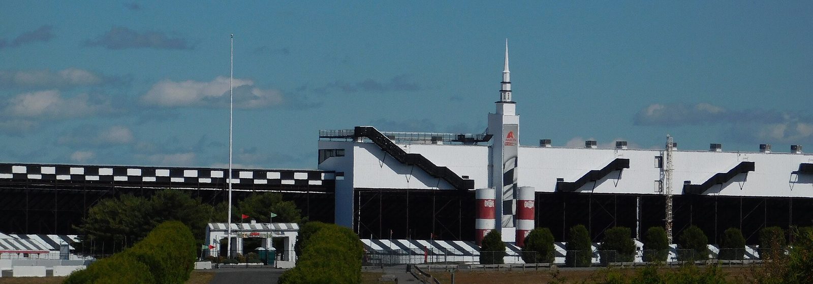 The main grandstand of Pocono Raceway, with its white spire and checkered trim, seen from the entrance drive in Long Pond, Pennsylvania - Pocono Raceway tickets