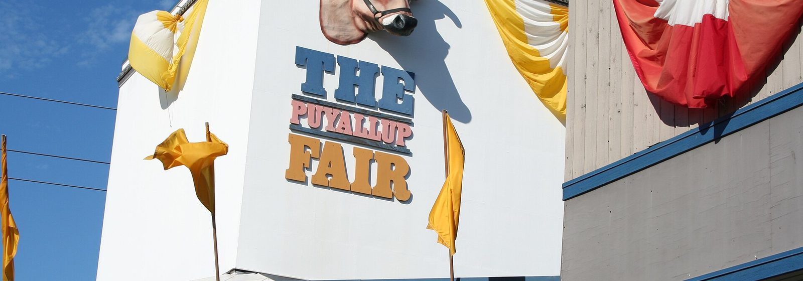 Entrance building of the Puyallup Fair, the Washington State Fair fairgrounds, in Puyallup, Washington, with its signature cow-head sign and banners - Puyallup Fairgrounds At Washington State Fair Events Center tickets